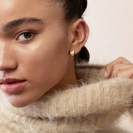 Gros plan sur les diamants taille rond sur les boucles d’oreilles en or rose, révélant leur brillance et la qualité du sertissage.