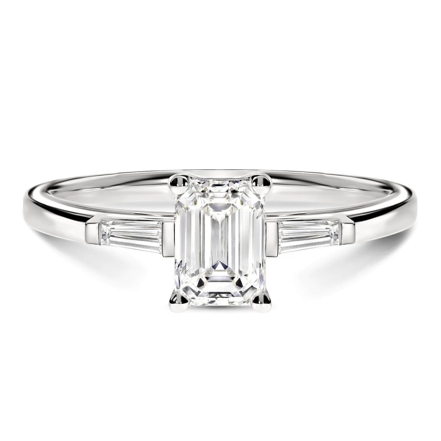 Gros plan du diamant émeraude sur la bague Trilogie en or blanc, mettant en valeur la brillance certifiée GIA
