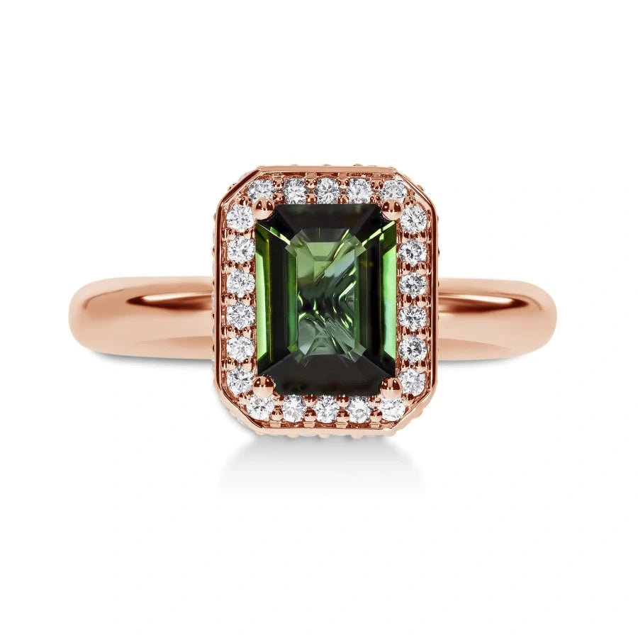 Gros plan de la tourmaline verte sur la bague Symbole en or rose, entourée d'un halo de lumière