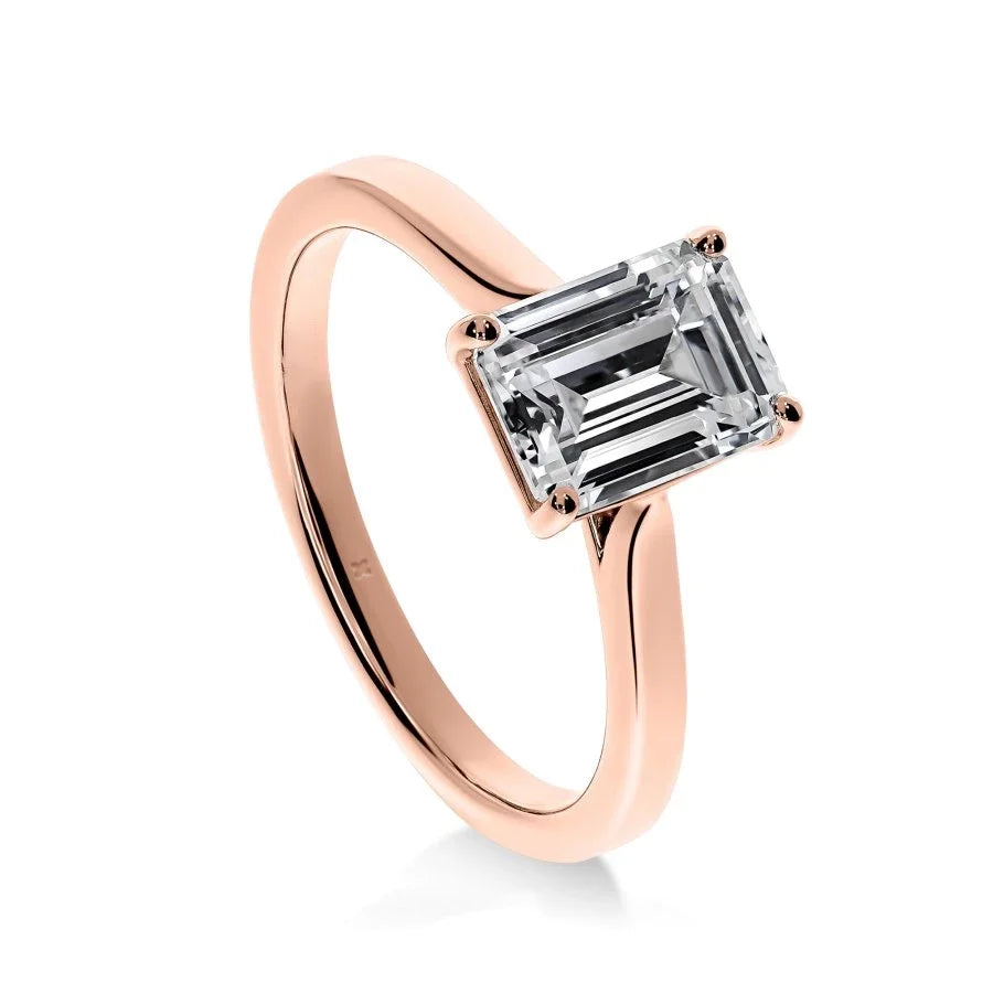 Gros plan de la bague Élégance en or rose, révélant la douceur des courbes et l'éclat du diamant émeraude.