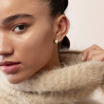 Gros plan sur les diamants taille rond sur les boucles d’oreilles en or rose, révélant leur brillance et la qualité du sertissage.