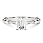 Gros plan du diamant émeraude sur la bague Trilogie en or blanc, mettant en valeur la brillance certifiée GIA