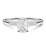 Gros plan du diamant émeraude sur la bague Trilogie en or blanc, mettant en valeur la brillance certifiée GIA