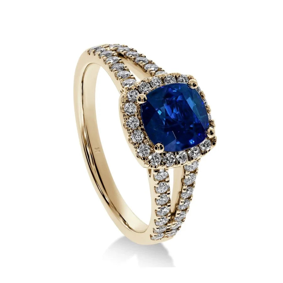 Gros plan du saphir bleu sur la bague Saphir Impérial en or jaune, mettant en valeur la taille coussin et le pavage de diamants