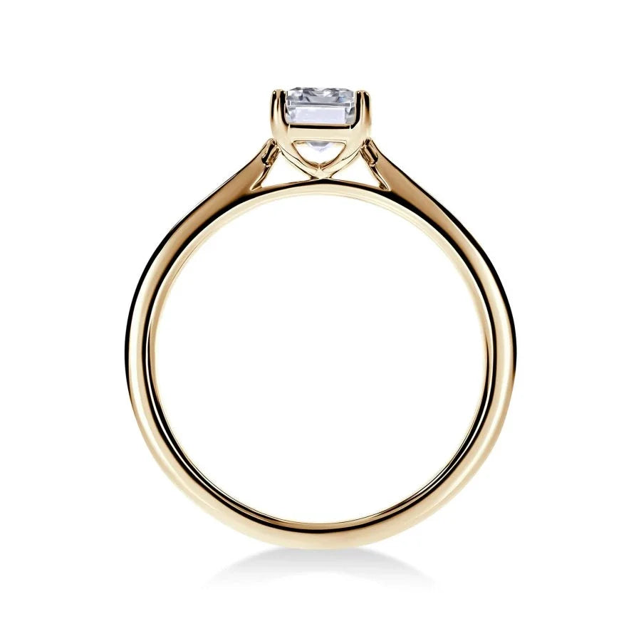Gros plan du diamant émeraude sur la bague Trésor en or jaune, mettant en valeur la brillance certifiée GIA.
